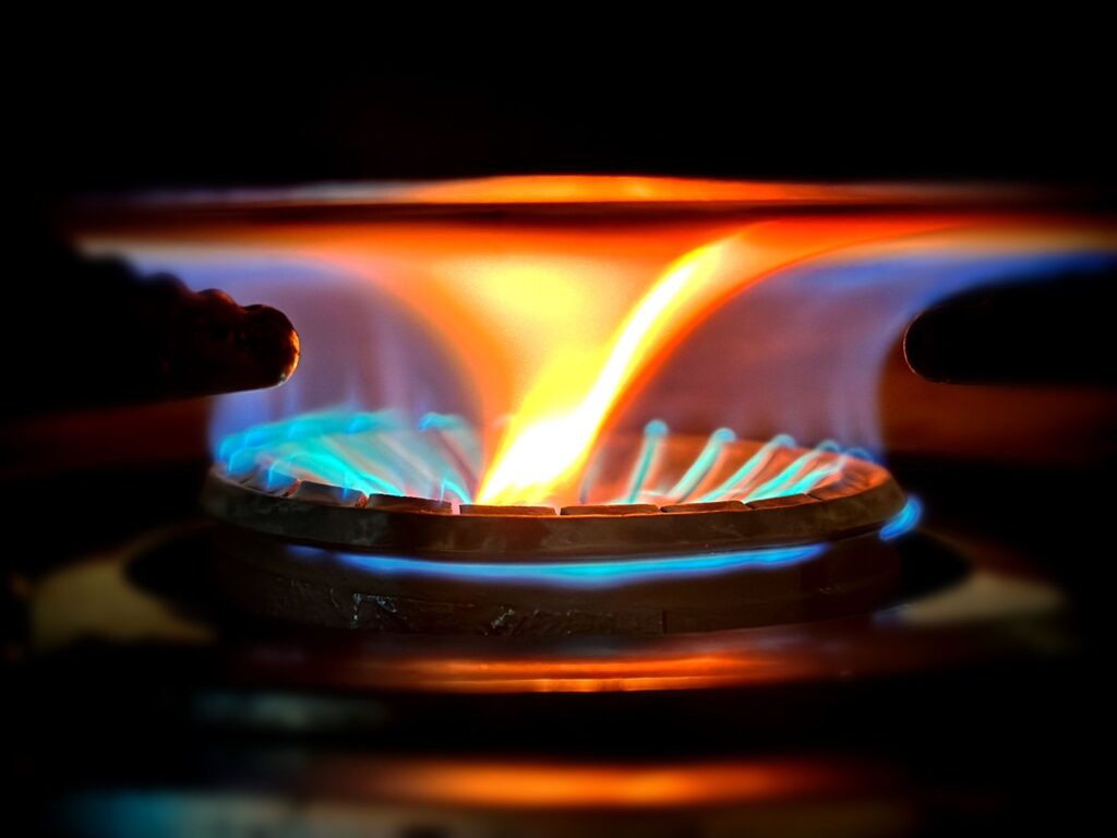 Api biru menyala pada burner kompor gas dari jarak dekat