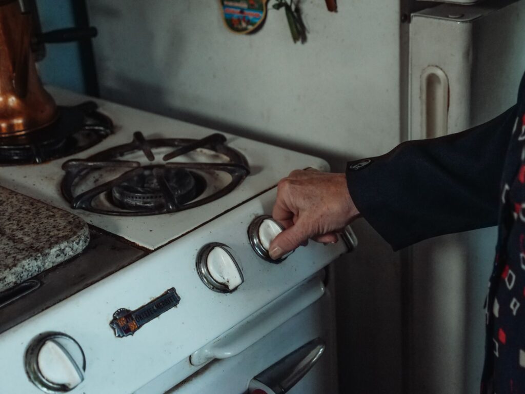 Tangan memutar knob kompor gas yang keras di dapur